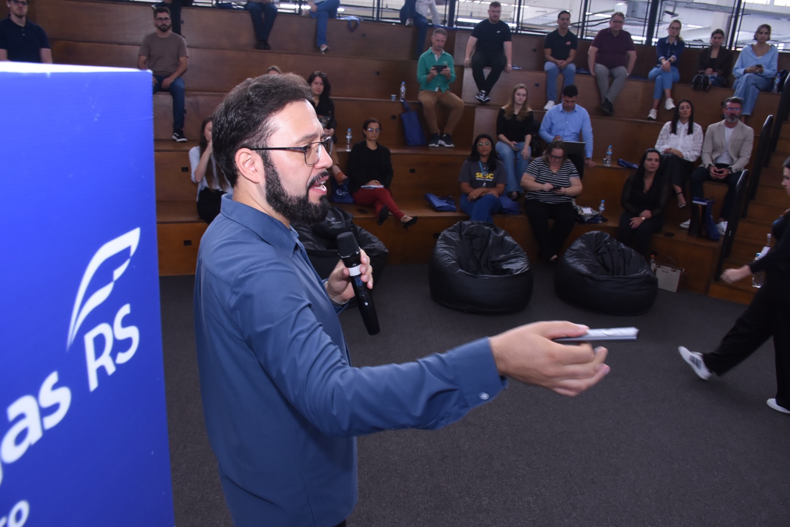 Calebe Salvia ensinando, com microfone na mão, diante de uma plateia de empresários